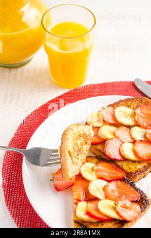 French Toast mit Erdbeeren, Banane und Honig. Orangensaft. Weißer Hintergrund Stockfoto