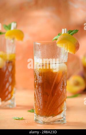 Pfirsich-Eistee-Kanne im Hintergrund. Schatten auf melonenfarbenem Hintergrund. Stockfoto