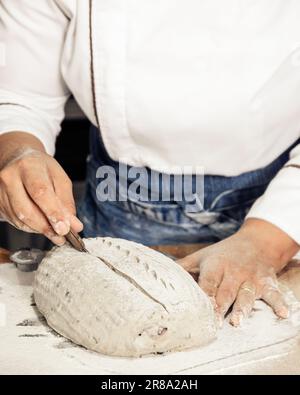 Kneten und Aufbereiten von Sauerteigbrot. Auf einem Holztisch. In der Bäckerei Stockfoto