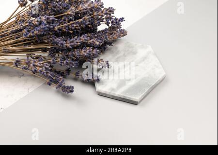 Lavendelblumen auf grauem und weißem Marmorhintergrund. Lavendelfarbener Blumenstrauß, Marmortablett. Speicherplatz kopieren. Stockfoto