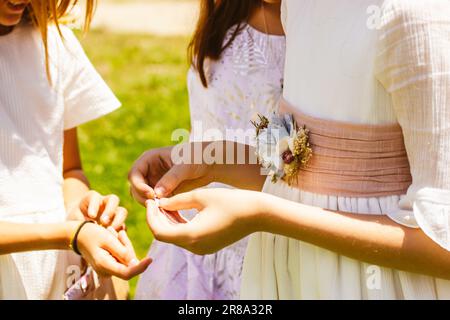 Drei kleine Mädchen - Brautjungfern - in klassischen, weißen Kleidern mit Band und Blumen. Freundinnen teilen Geheimnisse. Wirbellosigkeit, Zärtlichkeit, Kindheit. Ein Chi Stockfoto