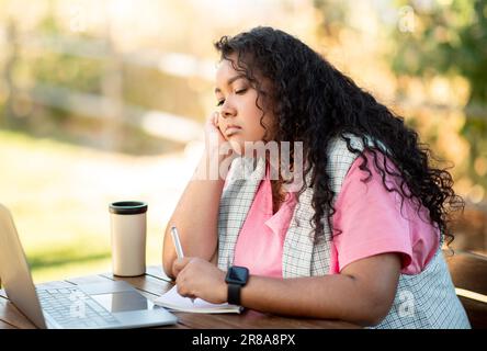 Eine Gelangweilte Studentin, Die Auf Einen Laptop Schaut Und Burnout Im Park Hat Stockfoto