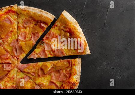 Flache hawaiianische Pizza, zubereitet in einem Holzofen. Schwarzer Hintergrund. Flache Ansicht und Schicht. Stockfoto