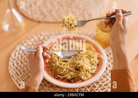 Eine Frau isst italienische Pasta mit Parmesankäse, Spaghetti wickeln sie mit einem Löffel um eine Gabel, pov-Shot Stockfoto