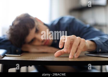 Arabic Man Erschöpft Von Überarbeitetem, Ruhendem Kopf Auf Tisch Drinnen Stockfoto