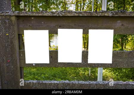 Drei leere weiße Noten auf einem alten Holzzaun im Sommer Stockfoto