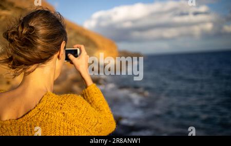 Hübsche, junge Frau, die während ihres Urlaubs Fotos mit ihrem Smartphone macht Stockfoto