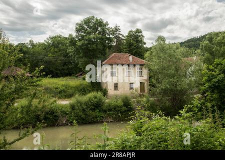 Ländliche Landschaft mit verlassenem Haus am Fluss an bewölkten Tagen Stockfoto