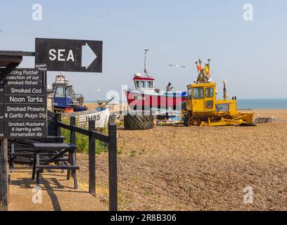 Aldeburgh, Suffolk, Großbritannien. Ein Schild auf einer Fischerhütte, das Räucherfisch verkauft, mit einem Fischerboot im Hintergrund. Stockfoto