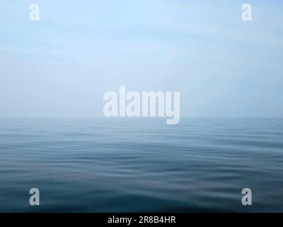 Ruhiges, blaues Wasser am Lake Michigan mit verschwommenem Horizont und Himmel Stockfoto
