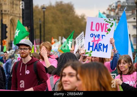 LONDON - 22. April 2023: Tauchen Sie ein in eine farbenfrohe Szene, in der XR-Demonstranten auf dem lebendigen Rebellion march, sprea, das Schild „Love over Harm“ halten Stockfoto