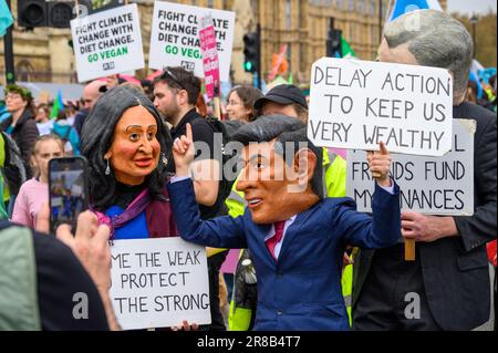 LONDON - 22. April 2023: Beeindruckende Szene, während XR-Demonstranten riesige Masken von Rishi Sunak und seiner Frau Akshata Murty tragen, die Zeichen für den Klimaschutz halten Stockfoto