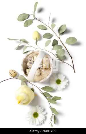 Korb mit Osterwachteleiern, Hähnchen, Kamillenblüten und Eukalyptuszweigen auf weißem Hintergrund Stockfoto