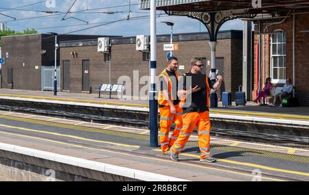 Bahnhof Grantham – Eisenbahningenieure oder Wartungspersonal, die einen Bahnsteig entlang laufen Stockfoto