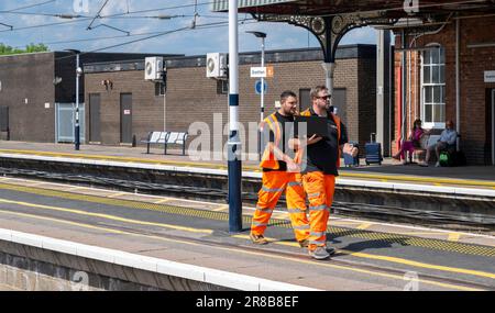 Bahnhof Grantham – Eisenbahningenieure oder Wartungspersonal, die einen Bahnsteig entlang laufen Stockfoto