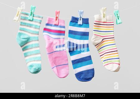 Verschiedene Socken, die vor hellem Hintergrund am Seil hängen Stockfoto