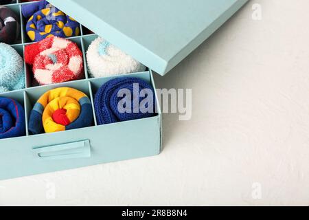 Schachtel mit verschiedenen Socken auf hellem Hintergrund, Nahaufnahme Stockfoto