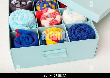 Schachtel mit verschiedenen Socken auf hellem Hintergrund, Nahaufnahme Stockfoto