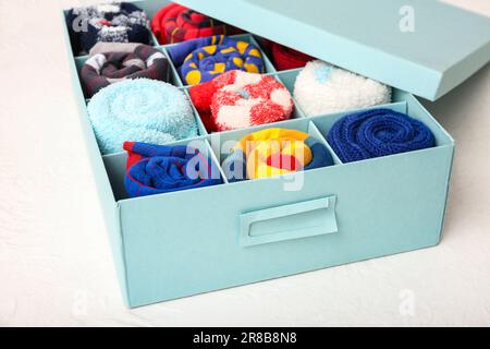 Schachtel mit verschiedenen Socken auf hellem Hintergrund, Nahaufnahme Stockfoto