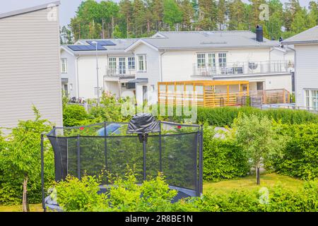 Wunderschöne Aussicht auf das Dorf mit Villen. Trampolin mit Schutznetz im Hof des Hauses. Stockfoto