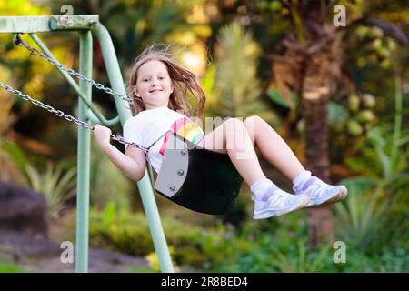 Kinderschaukel auf dem Spielplatz an einem sonnigen Sommertag in einem Park. Kinder schaukeln. Schule oder Kindergarten und Spielplatz. Stockfoto