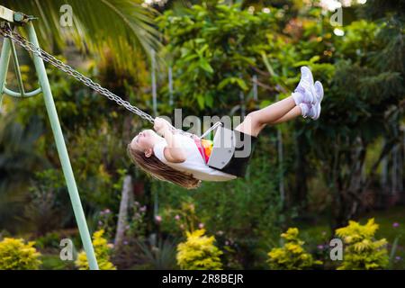 Kinderschaukel auf dem Spielplatz an einem sonnigen Sommertag in einem Park. Kinder schaukeln. Schule oder Kindergarten und Spielplatz. Stockfoto