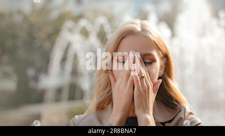 Junge Allergikerinnen leiden unter Allergien, wenn sie draußen auf der Straße der Stadt spazieren gehen Stockfoto