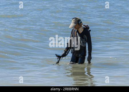 Ukraine, Iron Port - 01. September 2020: Ein Mann mit einem speziellen Gerät und Ausrüstung Metalldetektor auf der Suche nach verlorenen Schmuck und Gold im Meerwasser in der Nähe Stockfoto