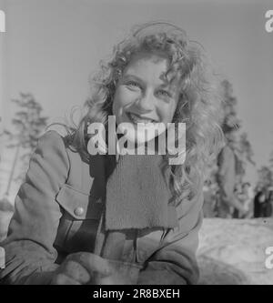 Aktuell 06-1950: Neue Seiten in Holmenkollen. In diesem Jahr war der Wind kurz davor, das gesamte Holmenkollrennet wegzublasen, aber nach einer dreistündigen Verschiebung verfiel es, und das große Volksfest, das alle anspricht, auch diejenigen, die sich nicht viel um den Sport kümmern, ging in der vorgeschriebenen Weise los. Hier sind Fotos des Fotografen Sverre A. Børretzen, die das Leben zeigen, das sich unter den 90.000 Zuschauern vor, während und nach dem Rennen entwickelt hat. Mette Friis, eine der vielen charmanten Zuschauer auf der diesjährigen Holmenkollrenn, lächelt schamlos über den Kaffee, der sich lange Zeit gut erwärmt hat Stockfoto