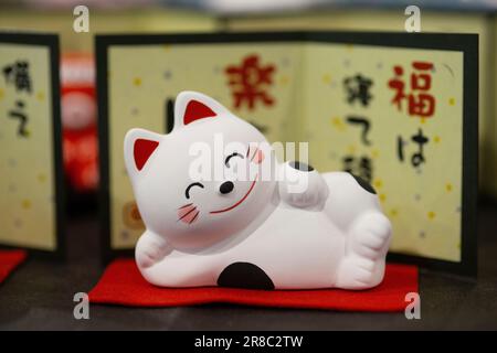 Maneki Neko Liegend, traditionelle winkende Katzenstatuen, auch bekannt als Maneki-neko Stockfoto