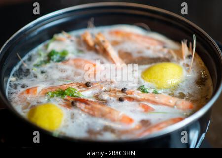 Große Riesengarnelen werden in einem Kochtopf gekocht. Kochen mit Gewürzen und Zitrone. Stockfoto