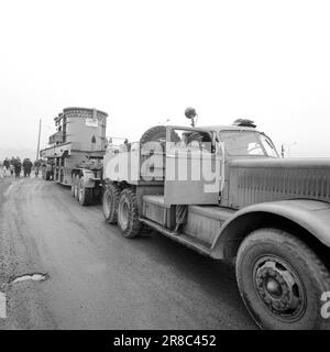 Aktuell 57-3-1960: Riese auf Stadtbesichtigung vierzig Räder, die neulich gemeinsam von Hasle nach Ulven in Oslo gerollt wurden. Sie führten eine historische Aufgabe aus: Der bisher größte in Norwegen gebaute Transformator – ein Riese von 205 Tonnen – wurde von per Kure A/S zum Standort der Beleuchtungsfirma in Ulven transportiert, wo er bei der Stromversorgung helfen wird. Der Transformator, der 161.000 Kilovoltampère erzeugt, ist 9,6 Meter lang und 5,7 Meter breit. Oslo Lysverker hatte Verstärkung für den Großtransport angefordert, und nicht weniger als zwei Fahrer waren im Geschäft. Sie erhielten ihre Fahrbefehle vom Komma Stockfoto