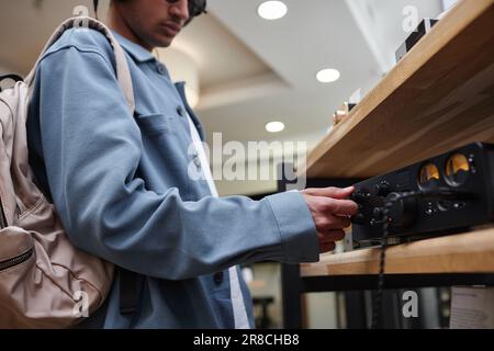 Nahaufnahme eines jungen Mannes, der Geräte im Musikladen aussteckt, Kopierraum Stockfoto