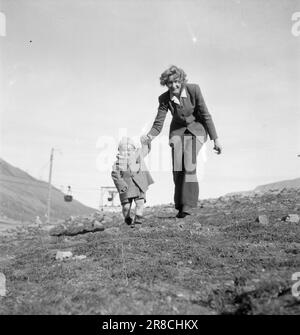 Derzeit 19-4-1947: Englische Dame in Svalbardenglisches Stadtmädchen für Polarnächte in Svalbard. Mrs. Kitty Thorbergsen traf Liebe in London, als sie als Bürodame im britischen Luftfahrtministerium arbeitete. In der Pension, in der sie wohnte, zog der Norweger per Thorbergsen schließlich ein, und es kam süße Musik. Jetzt sind sie verheiratet, haben Kinder und leben in Svalbard, wo per derzeit stationiert ist. Mrs. Thorbergsen ist unterwegs und trainiert Little Paul. Das Foto wurde im August gemacht, als wir hier zu Hause zu Fuß gingen, stöhnten und schwitzten, aber in Svalbard war es so kalt, dass Paul beide SoC tragen musste Stockfoto