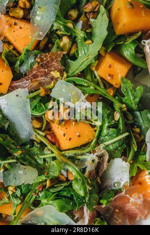 Nahaufnahme von Rucola-Salat mit Käse, Cantaloupe, Prosciutto, Pistazien Stockfoto