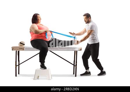 Physiotherapeutin hilft einer übergewichtigen Frau beim Training mit einem Stretching-Band auf weißem Hintergrund Stockfoto