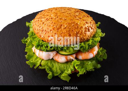 Burger mit Sesambrötchen, Garnelen, frischem grünen Salat und Gurken. Stockfoto
