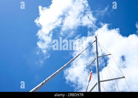 Ein Mast eines Segelbootes mit blauem Himmel und weißen Wolken Stockfoto