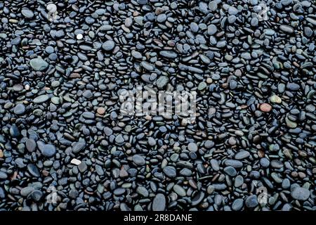 Schwarze nasse Steine Basaltsäulen an der Uferküste des Flusses Stockfoto