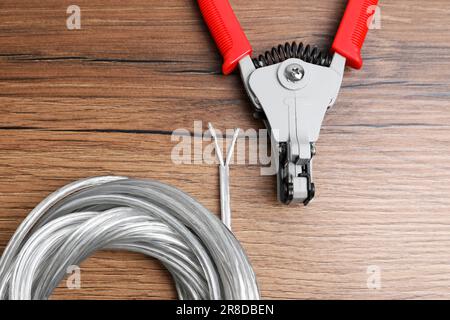 Schneider und Kabel mit abisoliertem Draht auf Holztisch, flach verlegt Stockfoto