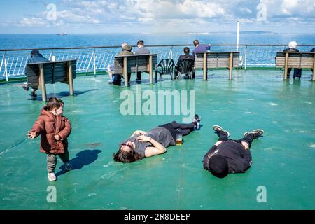 Ein kleines Kind beobachtet zwei schlafende Passagiere an Bord Einer DFDS Cross Channel Ferry vor der Sussex Coast, Großbritannien. Stockfoto