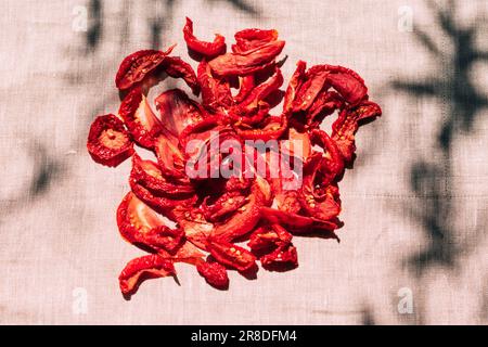 Auf dem Küchentisch liegen köstliche, sonnengetrocknete Tomaten, helles Sonnenlicht und Schatten, Blick von oben. Ernte und Verarbeitung von Gemüse, Bio-Lebensmitteln Stockfoto