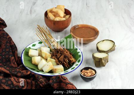 Sate Padang, traditionelles Essen Rindfleisch Satay aus Padang Indonesien. Serviert mit Lontong oder Ketupat, komprimiertem Reiskuchen und gelber Spezialsauce Stockfoto