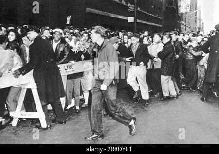 New York, New York: 23. Februar 1957 Teenage Rock 'n' Roll-Fans auf der 44. Street werden von der Polizei festgehalten, während sie sich anstellen, um den Disc-Jockey Alan Freed und den Film „Don't Knock the Rock“ zu sehen. Stockfoto