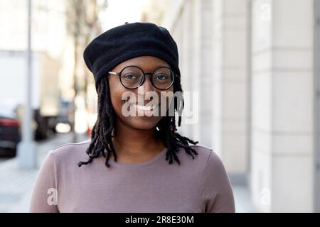 Porträt einer lächelnden Frau mit Brille und Baskenmütze in der Stadt Stockfoto