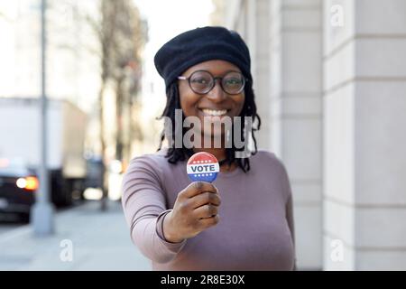 Porträt einer lächelnden Frau mit Wahlknopf in der Stadt Stockfoto