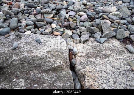 Glatte graue Kieselsteine an einer ruhigen Küste von Massachusets Stockfoto