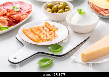 Vorspeisen mit verschiedenen Antipasti, Wurstwaren, Snacks, Fleischplatte mit Käse und scharfen Oliven, Lachs-Carpaccio und Tomatensalat Stockfoto