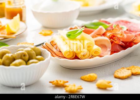 Vorspeisen mit verschiedenen Antipasti, Wurstwaren, Snacks, Fleischplatte mit Käse und scharfen Oliven, Lachs-Carpaccio und Tomatensalat Stockfoto
