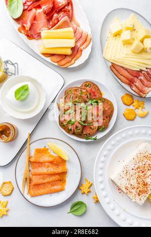 Vorspeisen mit verschiedenen Antipasti, Wurstwaren, Snacks, Fleischplatte mit Käse und scharfen Oliven, Lachs-Carpaccio und Tomatensalat Stockfoto